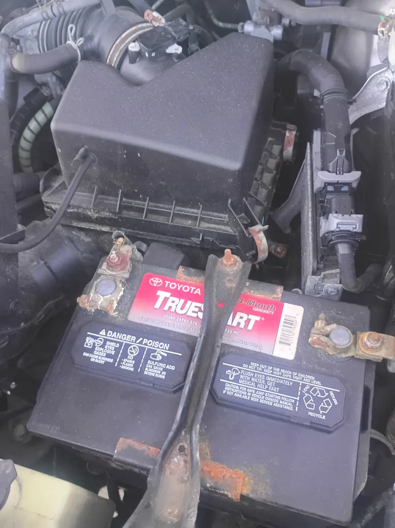 Heavily corroded positive and negative battery terminals on a Toyota TrueStart battery under the hood