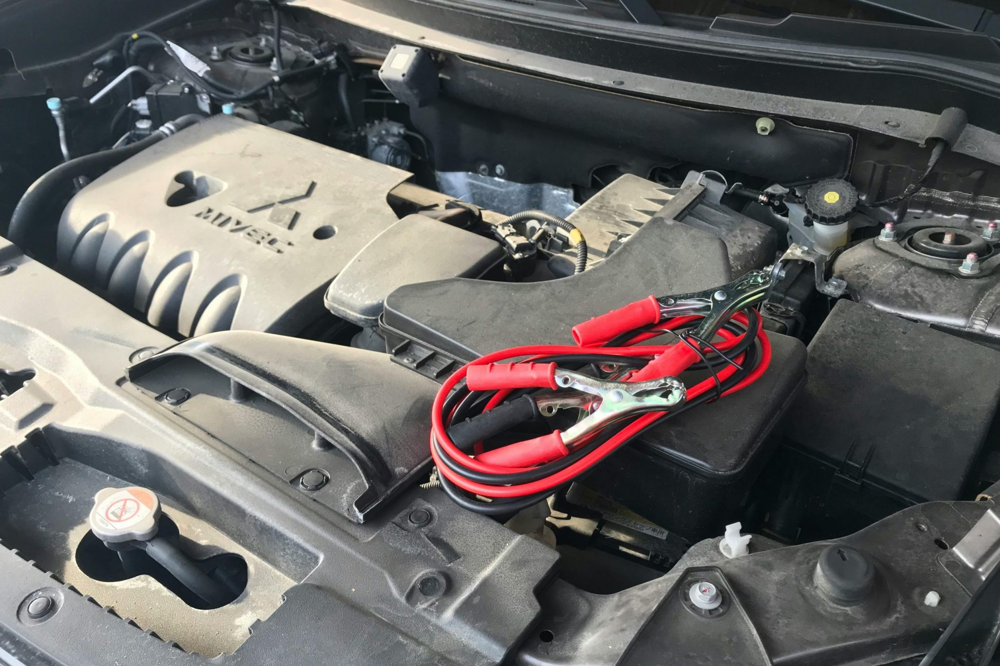 Detailed view of a car engine with red jumper cables, ideal for automotive themes.